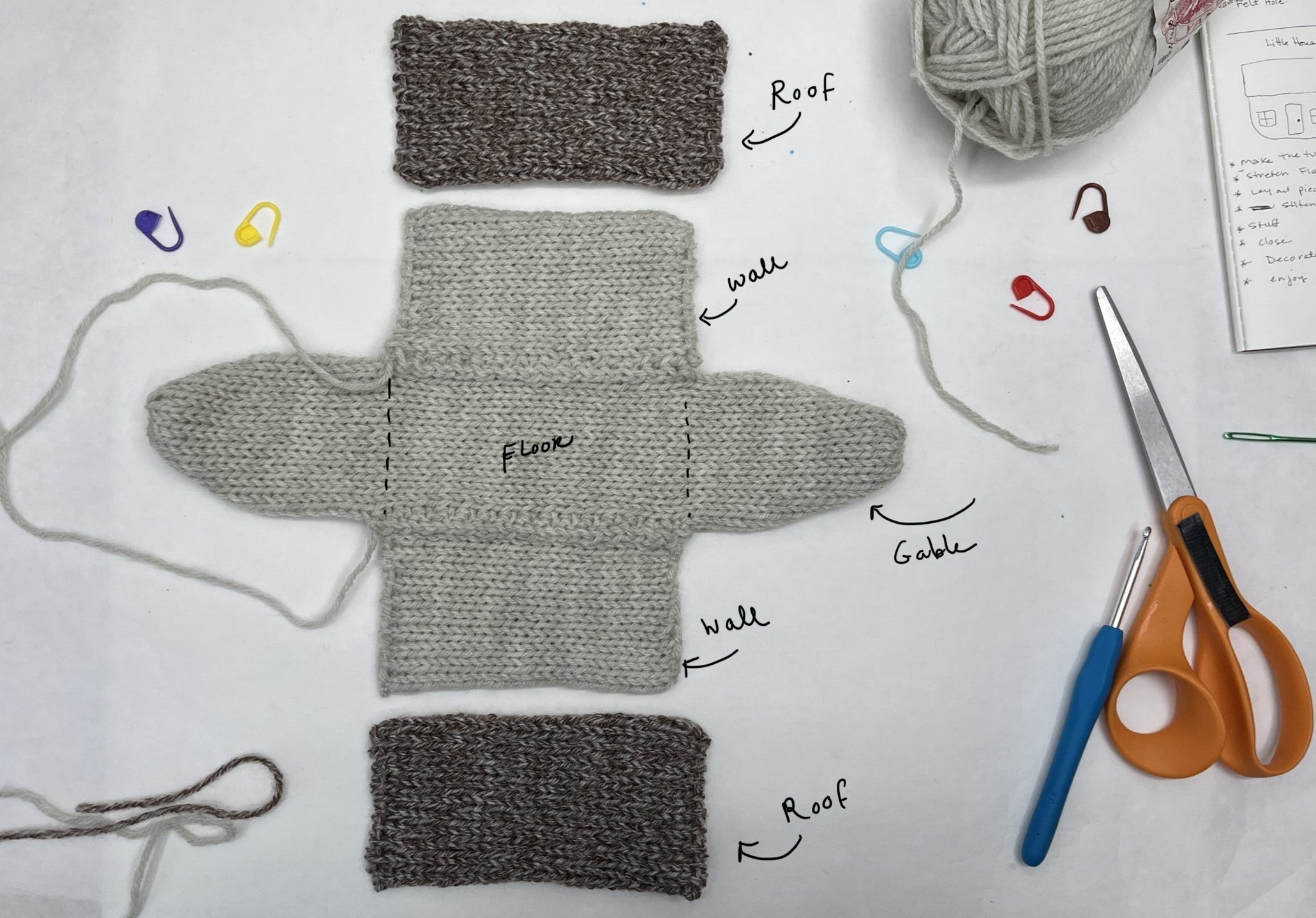 Knitted rectangles laid out flat next to each other to form a soft house toy